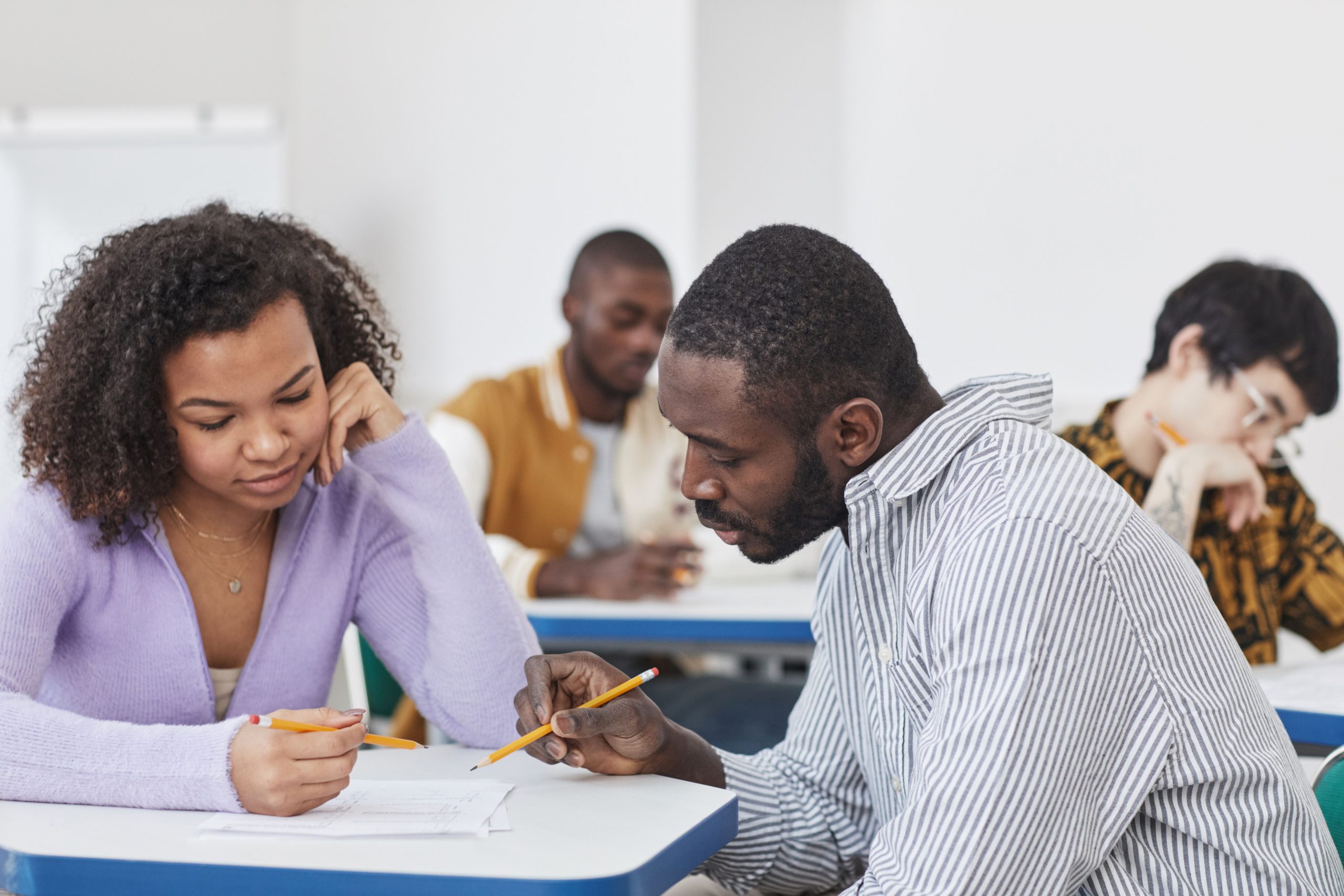 A diverse group of students collaborating in an educational environment, focusing on their assignments.