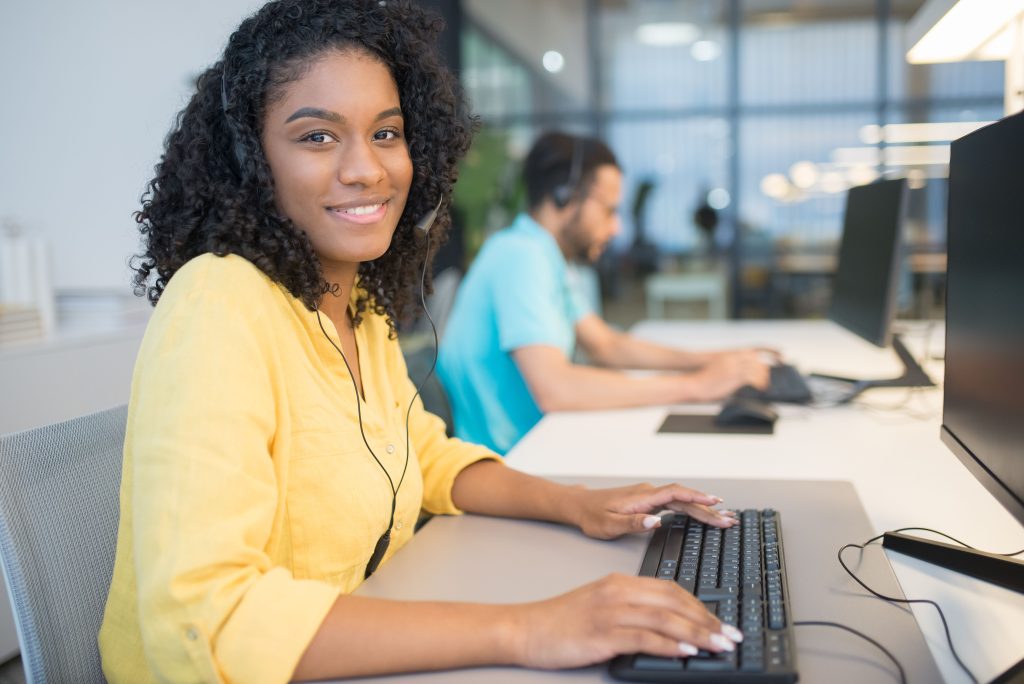 Smiling customer support representatives working in a modern office environment, emphasizing teamwork and efficiency.
